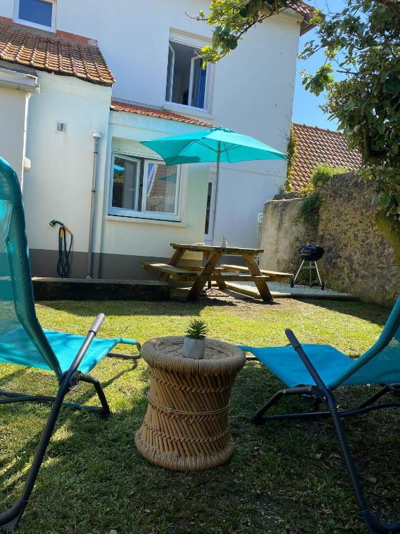 a patio with two chairs and a table and an umbrella at Le Petit Noirda in Audresselles