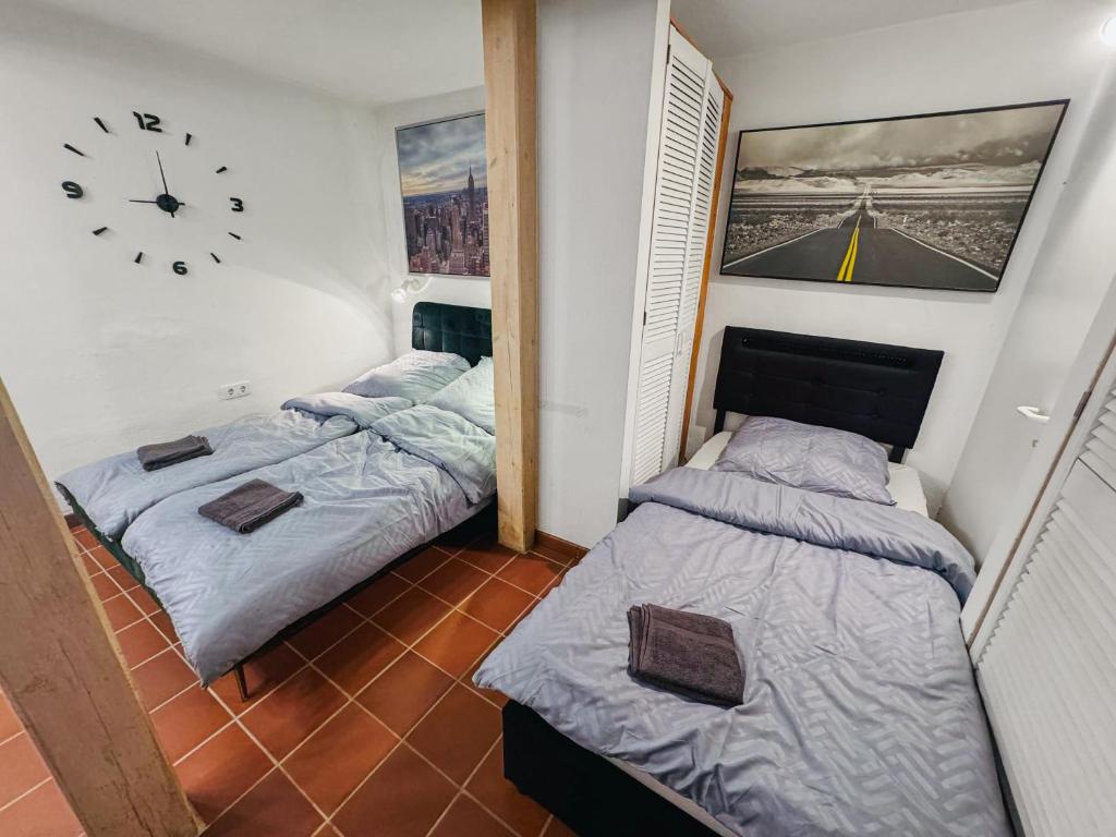 two beds in a room with a clock on the wall at RheinOase mit Garten für Familien & Gruppen in Koblenz