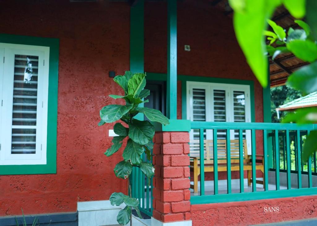 una casa con un porche delantero verde y rojo en Paddy Land, en Wayanad