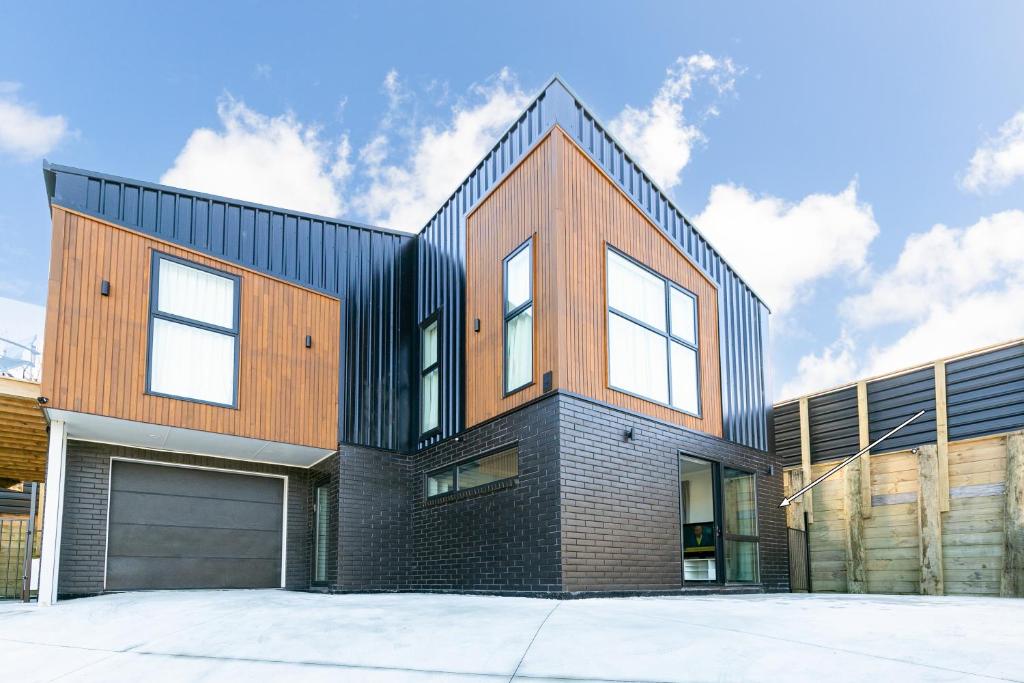 a black and wooden house with a garage at Modern 1 Bed Smart Flat in Upper Hutt with Full Kitchen, Parking - 5 minutes to Brewtown in Upper Hutt