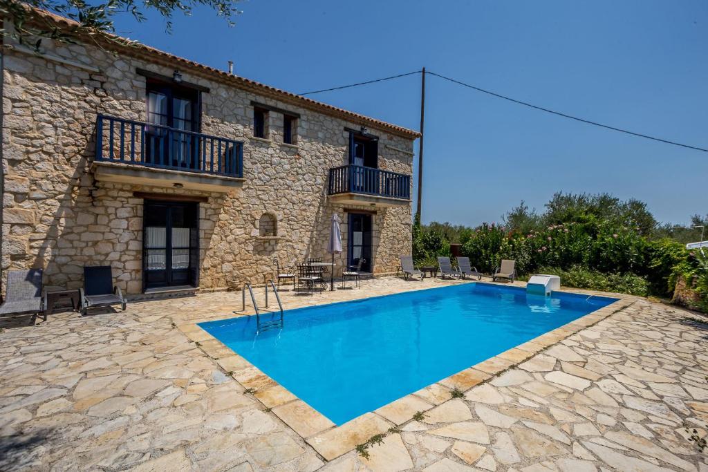 a swimming pool in front of a stone house at Villa Afroditi Aresti by Sealand Villas in Áyios Dhimítrios