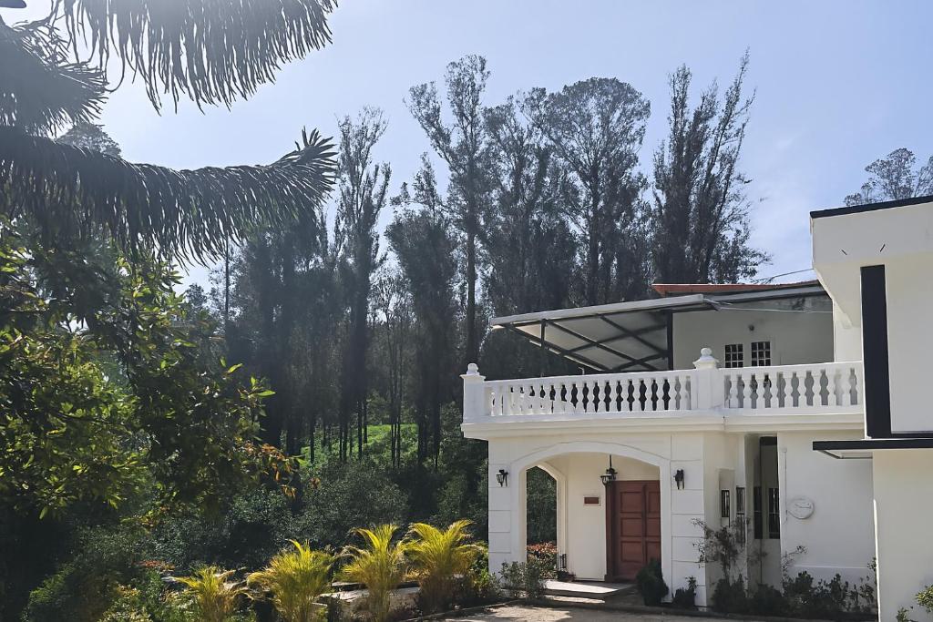 a white house with a balcony and trees at Pear Tree Luxe Entire 3BHK Villa - Only For Family in Kotagiri