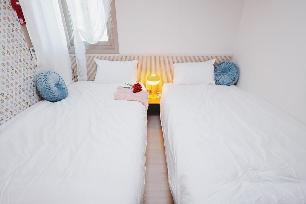 two beds in a room with white sheets and blue pillows at 레토하우스 