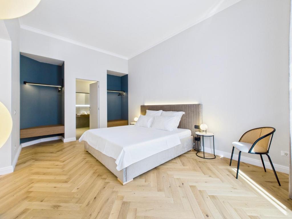 a bedroom with a white bed and a chair at Griselini Boutique Suites in Timişoara