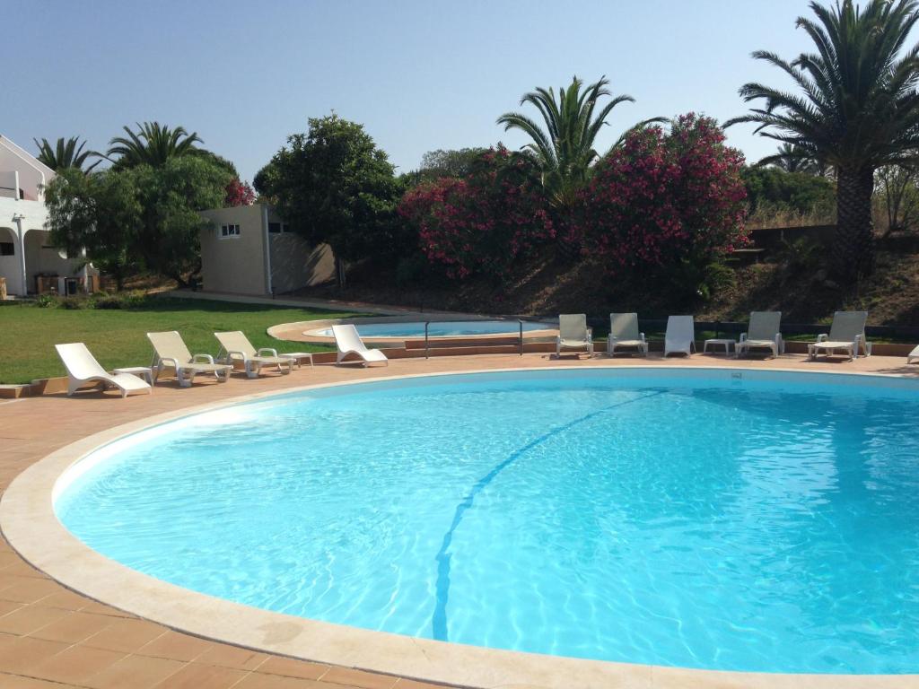 a large swimming pool with lounge chairs and trees at Vilamar in Luz