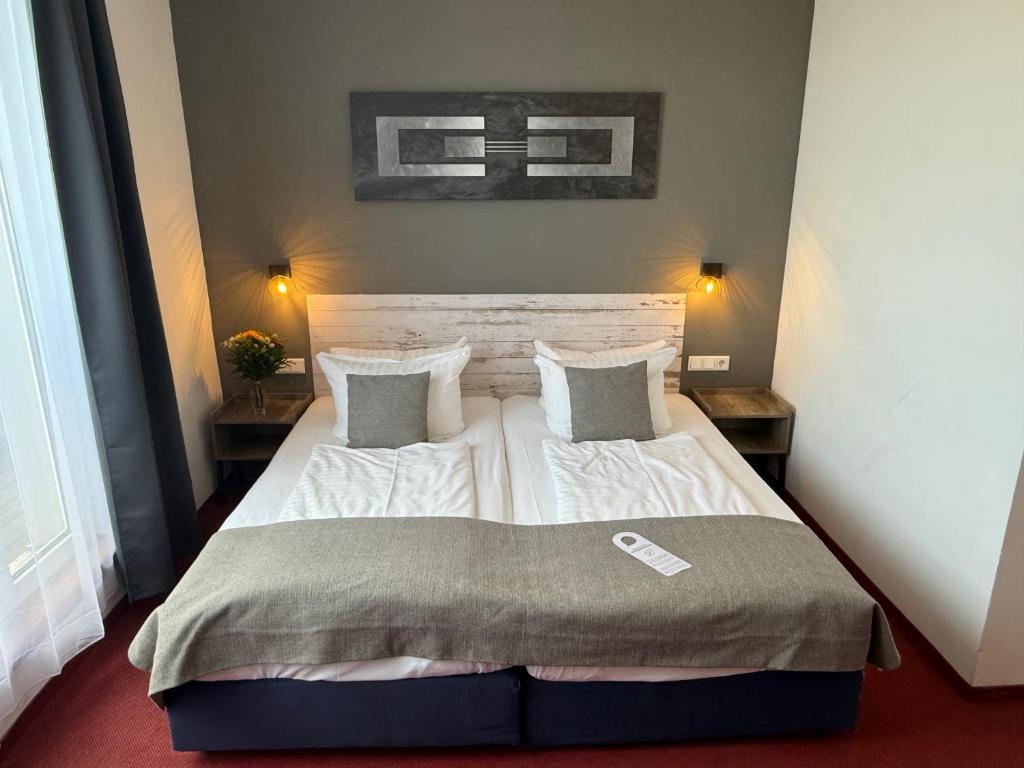 a bedroom with a large white bed with two pillows at Hotel Aviva in Leipzig