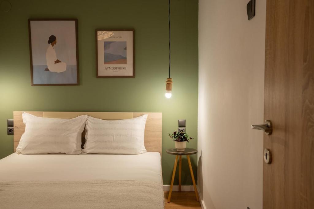 a bedroom with a white bed and a green wall at The Uppertown Nest - By Urban Minds in Thessaloniki