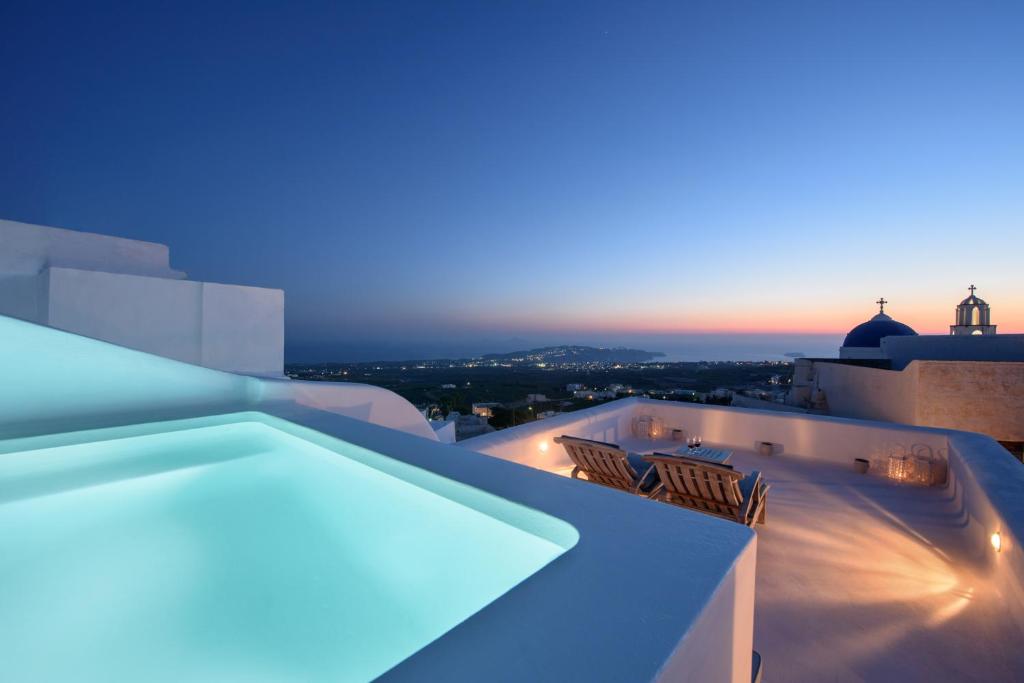a rooftop with chairs and a swimming pool at night at Sensation Villa - by Senses Collection in Pyrgos