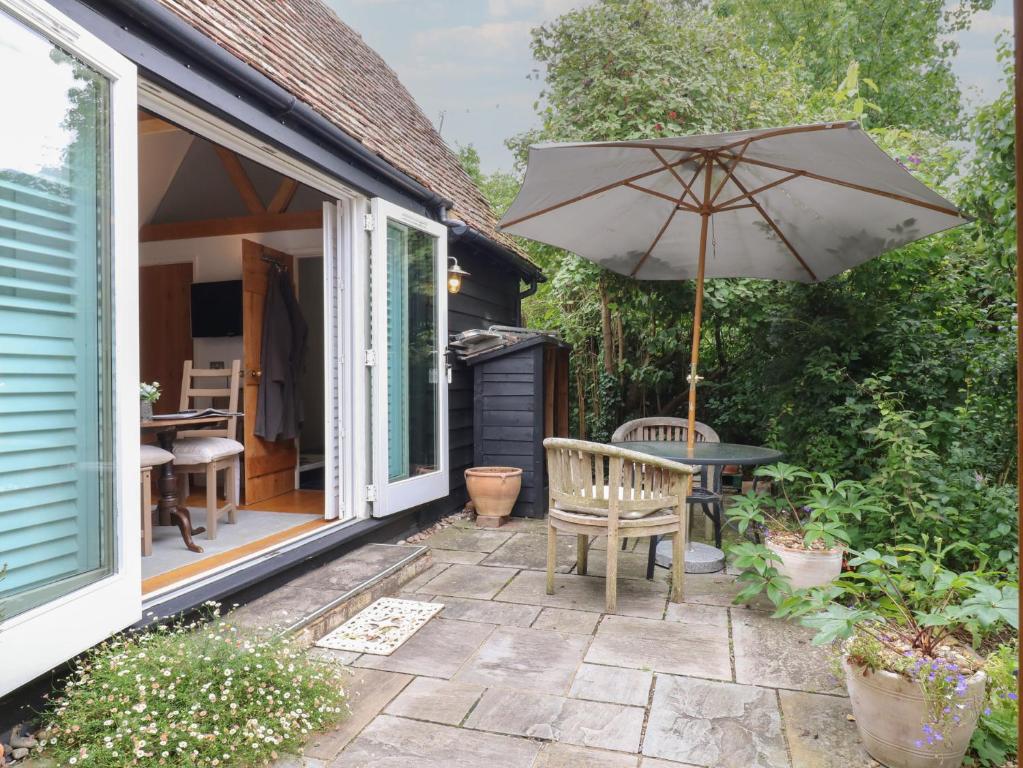 a patio with a table and an umbrella at Little Barn in Royston