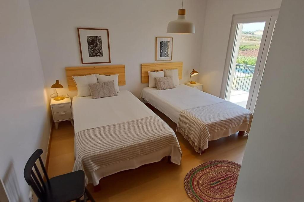 a bedroom with two beds and a window at Casa Condor - Moradia com piscina a 5 min da praia in Lourinhã