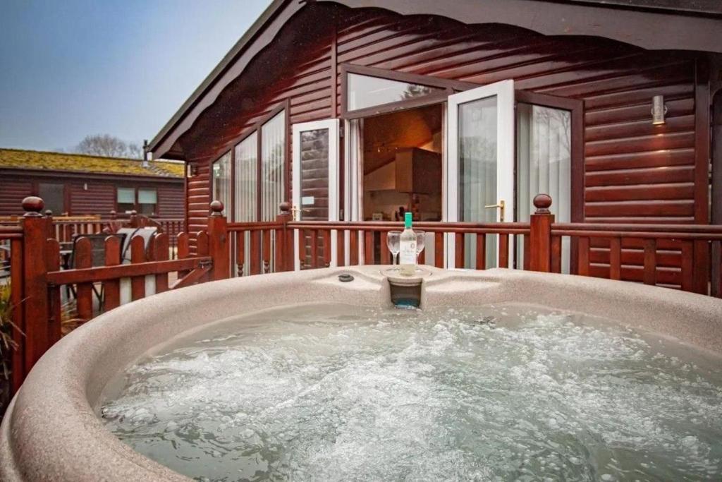 a hot tub in front of a wooden house at Lakeside 1, White Cross Bay, Windermere in Windermere