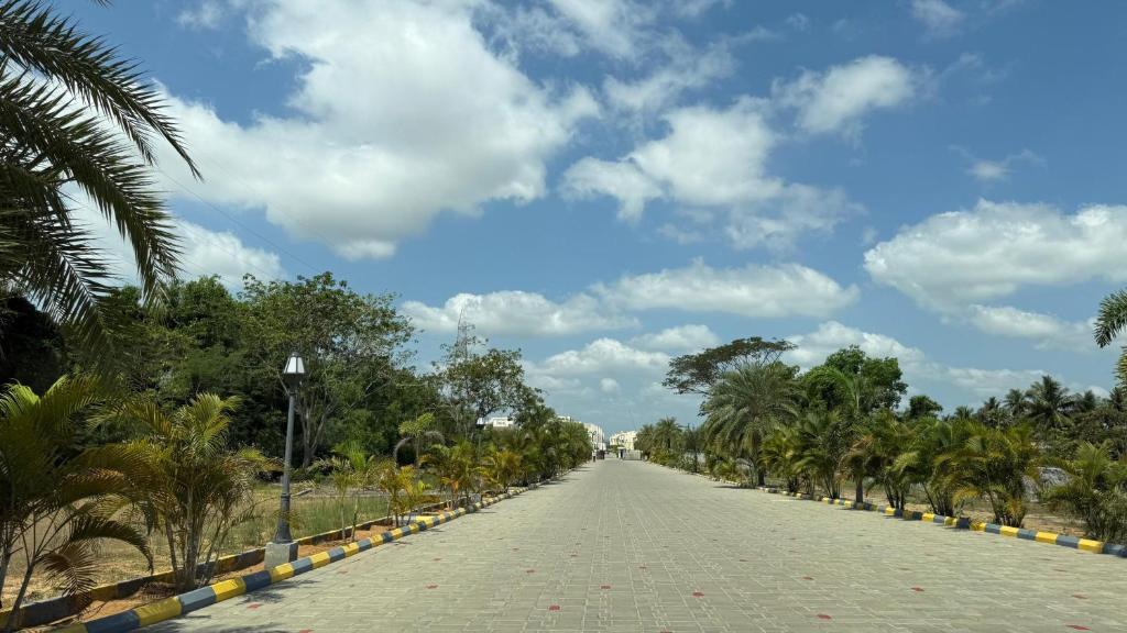 a road lined with palm trees and a cloudy sky at Silver Sand resorts With Swimming Pool in Chennai