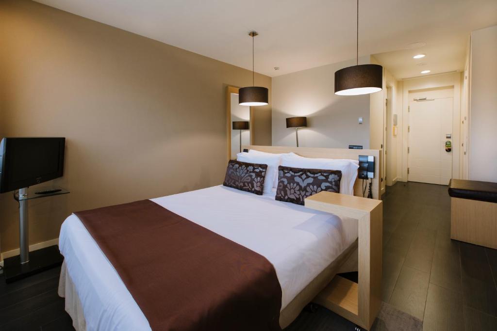 a hotel room with a large bed and a flat screen tv at PCM Forum Alcalá in Alcalá de Henares
