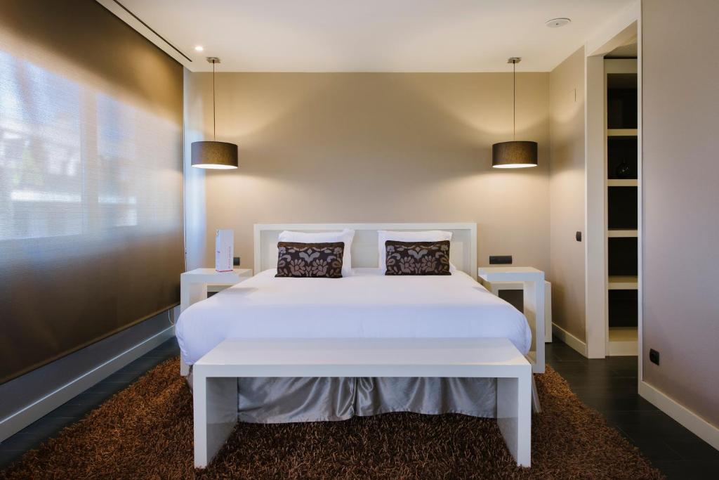a bedroom with a white bed with two tables at PCM Forum Alcalá in Alcalá de Henares