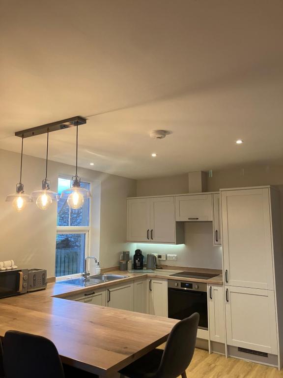 a kitchen with white cabinets and a wooden table at Quina Holiday Home in Finstown