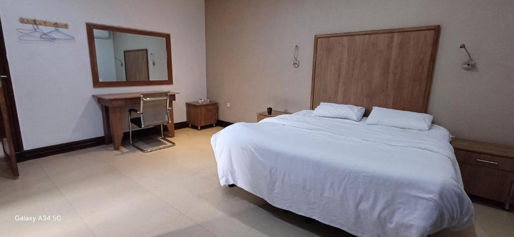 Un dormitorio con una gran cama blanca y un escritorio. en Town houses, en Lusaka