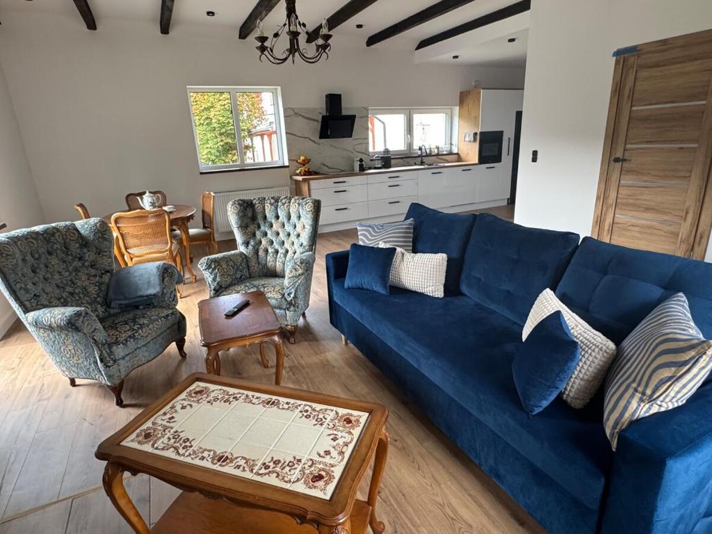 a living room with a blue couch and chairs at Dom przy lesie in Koniecwałd