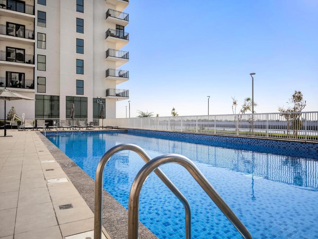 a swimming pool in front of a building at FIRST CLASS 1BR Tranquility in Style in Abu Dhabi