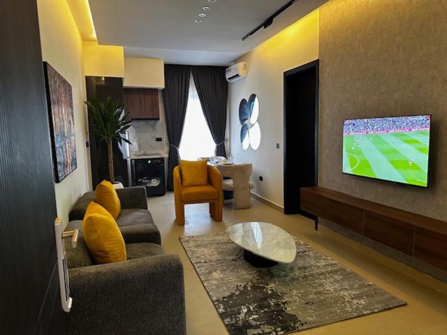 a living room with a couch and a tv on a wall at SIO APARTMENTs in Lekki