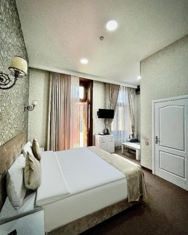 a bedroom with a large white bed and a window at Nizami Hotel Baku in Baku