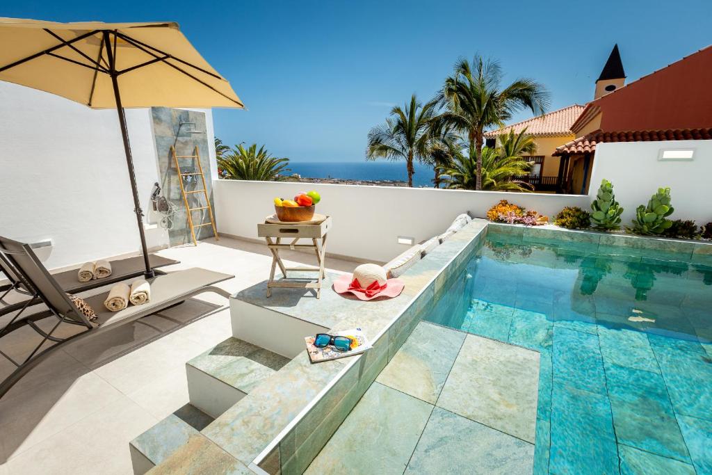a swimming pool with an umbrella next to a villa at Exclusive Villa FRANJULY Playa Paraiso Ocean View Private Pool Large Terrace in Adeje