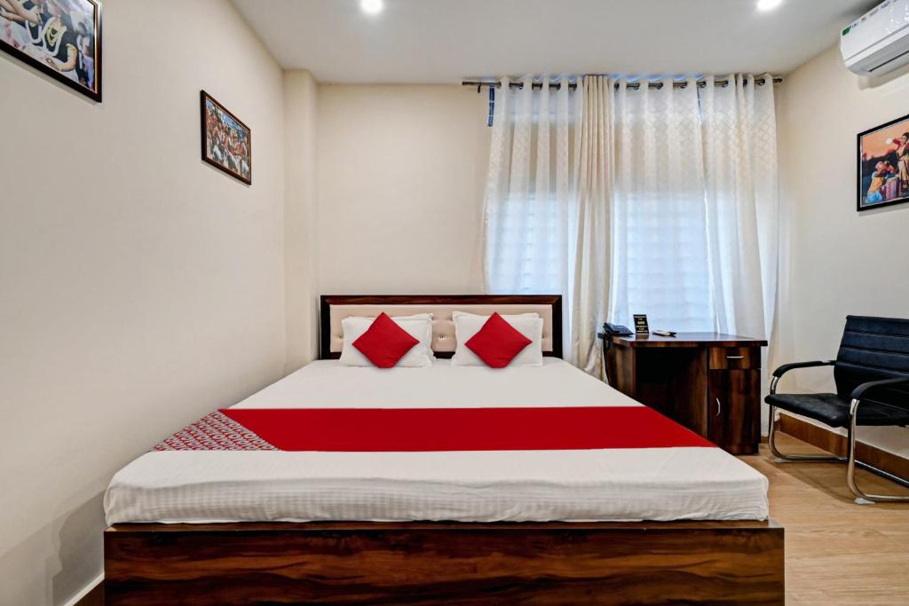 a bedroom with a bed with red pillows and a chair at Hotel O Axom Inn in Barpeta