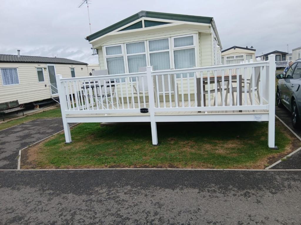 a white bench in front of a house at Willerby Delux - Holiday Home by the Sea - close to the Entertainment Complex-bedding, towels & wifi Included! in Jaywick Sands