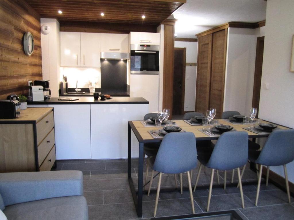 a kitchen with a table and blue chairs in a room at Résidence La Bergerie - Appartement 2 pièces chaleureux et bien équipé MAE-2223 in Bonneval-sur-Arc