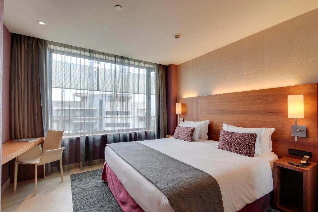 a hotel room with a bed and a desk and a window at Hotel Badalona Tower in Badalona