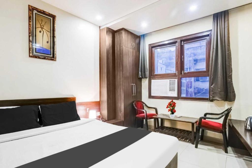 a bedroom with a bed and a desk and a window at Super Hotel O Sindhi Camp Formerly Hotel Paul Avenue in Jaipur