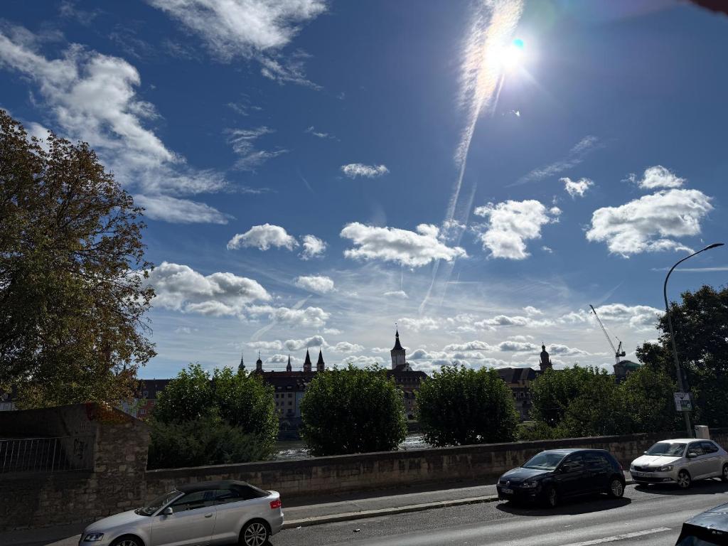 two cars driving down a road with the sun in the sky at Wohnen am Main in Würzburg