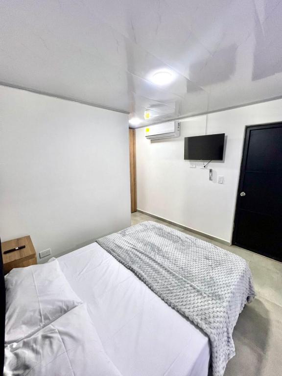 a bedroom with a white bed and a flat screen tv at GM Suites in Cúcuta