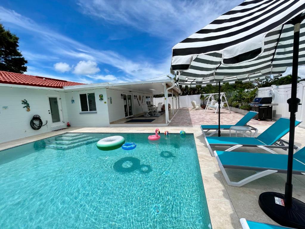 a swimming pool with two chairs and an umbrella at Madeira Beach retreat in Seminole