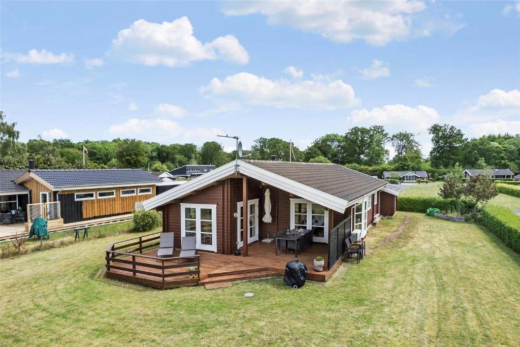 una piccola casa con un ampio ponte su un cortile di 40505-Juelsminde-Pot-Strandby-326 a Sønderby