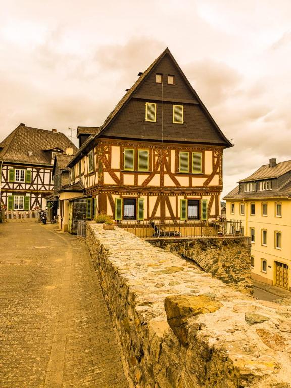 a large wooden house in a town with a stone wall at Pension bei Goscha mit Schlossblick in Braunfels