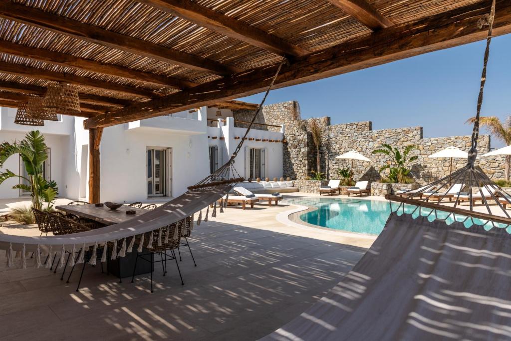 a villa with a swimming pool and a hammock at Blue Diamond BESTOFMIKONOS in Ornos