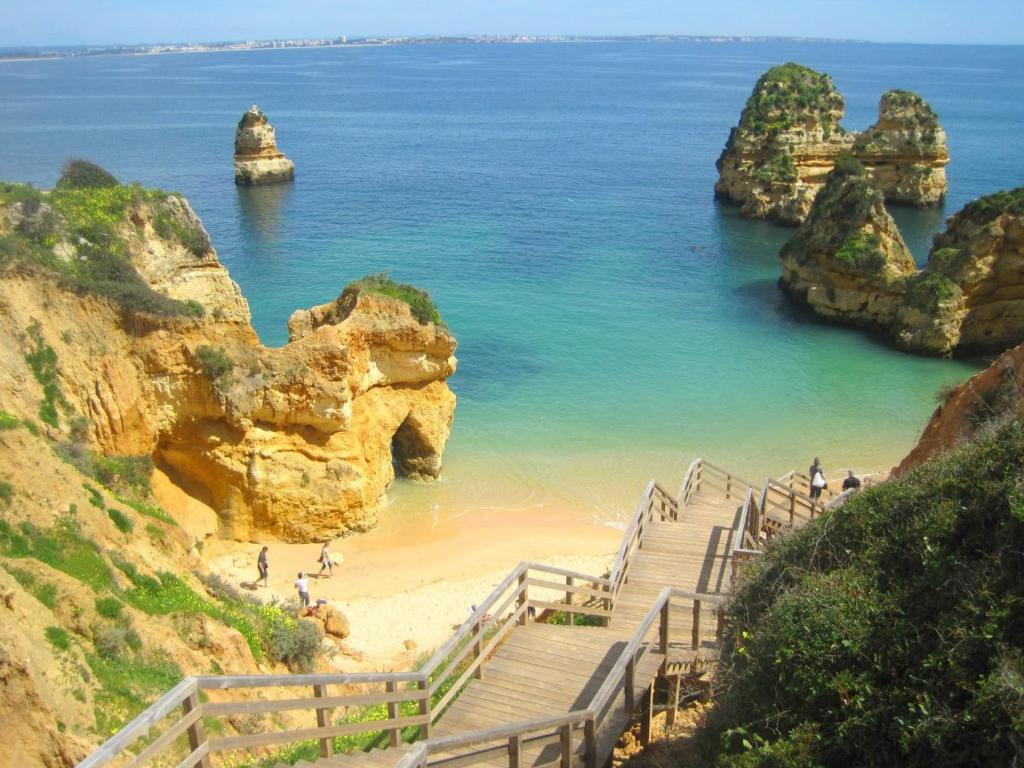 a staircase leading to a beach with rocks in the ocean at Vilamar in Luz