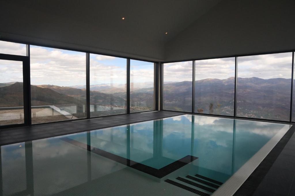 a swimming pool in a building with mountains in the background at Silken Mezio National Park in Soajo