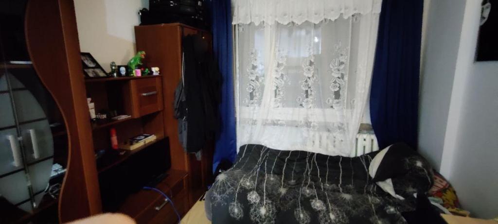 a bedroom with a bed and a window with blue curtains at Karola Szymanowskiego 2 Apart in Chełm