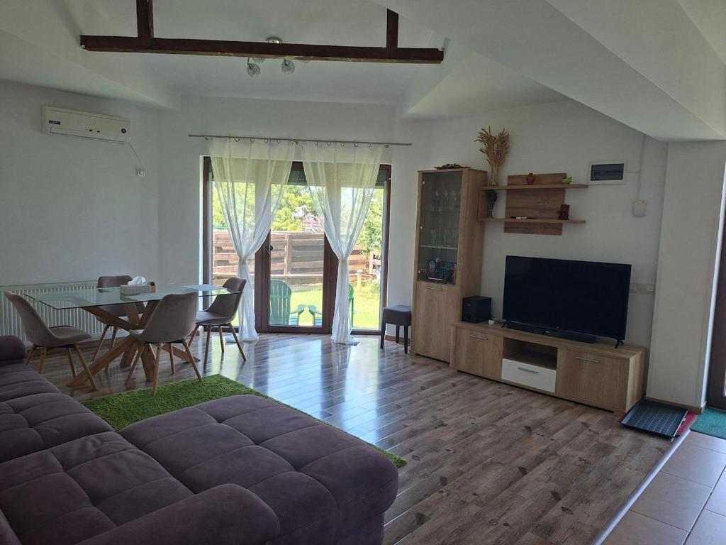 Una sala de estar con un sofá, una mesa y un televisor. en Jardin Maison - Therme- self access, en Baloteşti