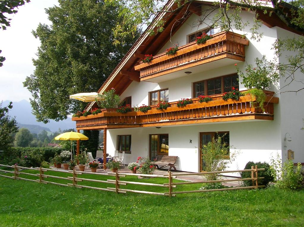 ein weißes Haus mit einem Balkon und einem Sonnenschirm in der Unterkunft Landhaus Heinrich in Ruhpolding