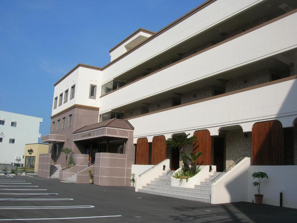a large white building with stairs in a street at Hotel Luandon Shirahama in Shirahama