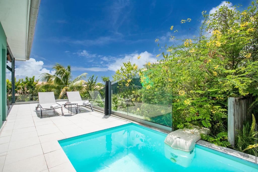 レ・トロワ・イレにあるVilla Hateya, vue mer et piscine privéeの家の隣に椅子2脚付きのスイミングプール