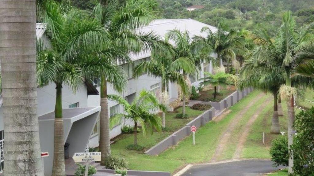 a row of palm trees next to a white building at Unit51 MarinaGlen Holiday Resort in Marina Beach