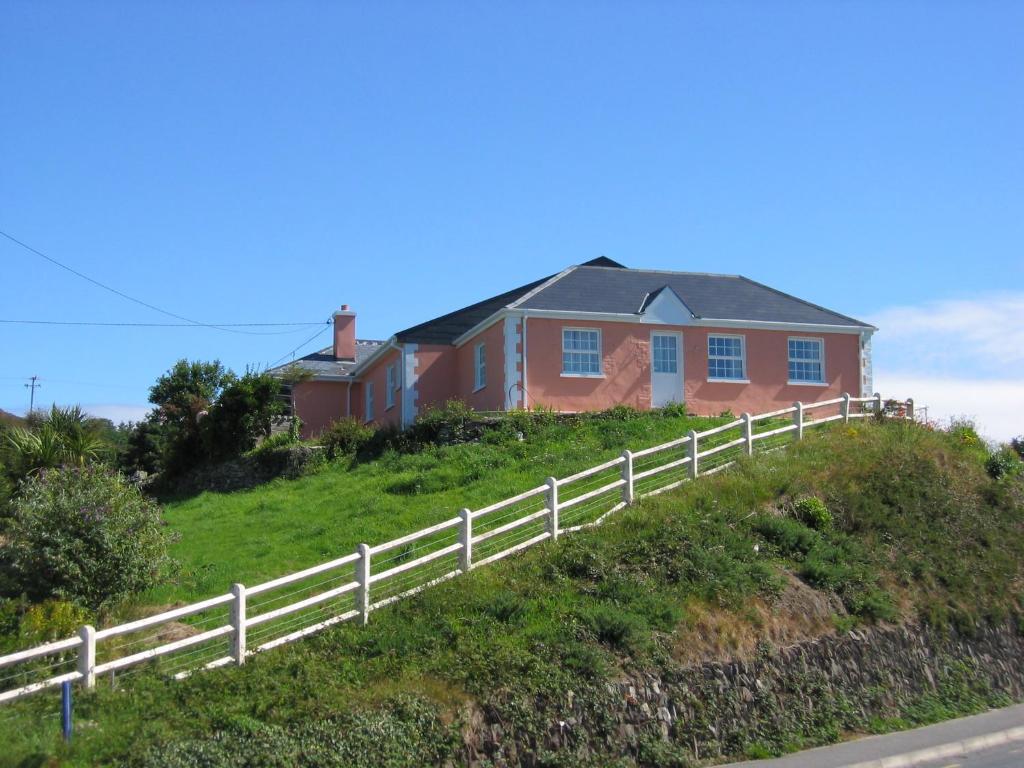 uma casa no topo de uma colina com uma cerca em Cottage Heights em Castletownbere