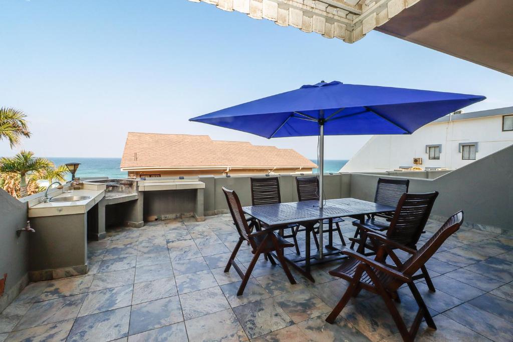 a table and chairs on a balcony with an umbrella at Carrick-A-Rede 7 in Margate