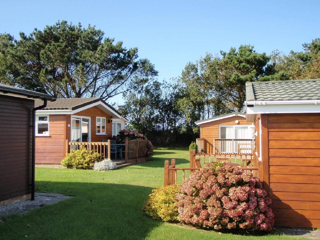 ein Haus mit einem Zaun und einem Garten mit einem Hof in der Unterkunft Chalets & Lodges at Atlantic Bays Holiday Park in Padstow