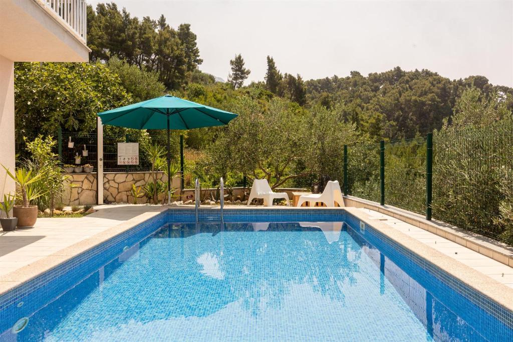 a swimming pool with an umbrella next to a house at Apartments Seaview in Tučepi