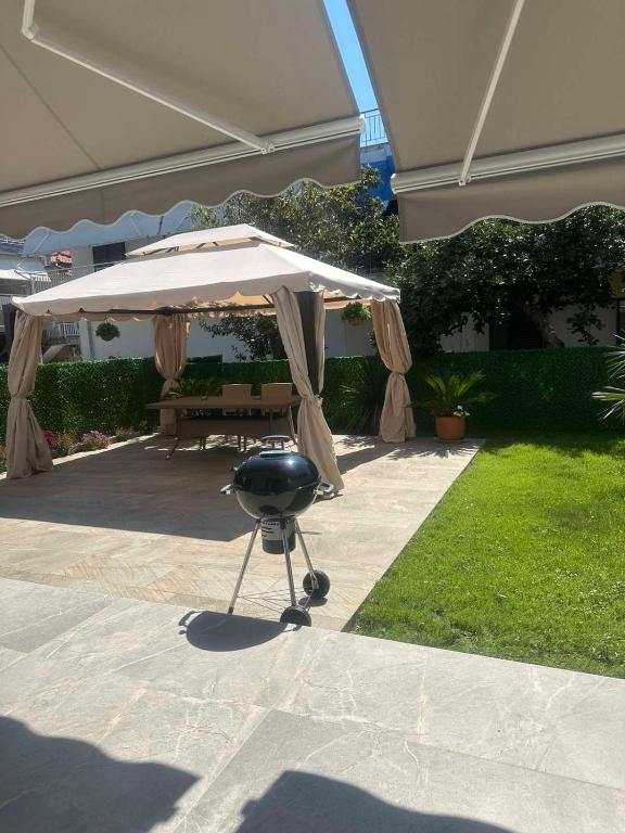 a grill under an umbrella on a patio at Самостоятелно студио с градина in Asprovalta