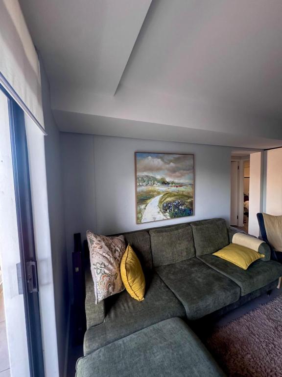 a living room with a green couch with yellow pillows at Cosy Flat Steps from the Beach in Cape Town